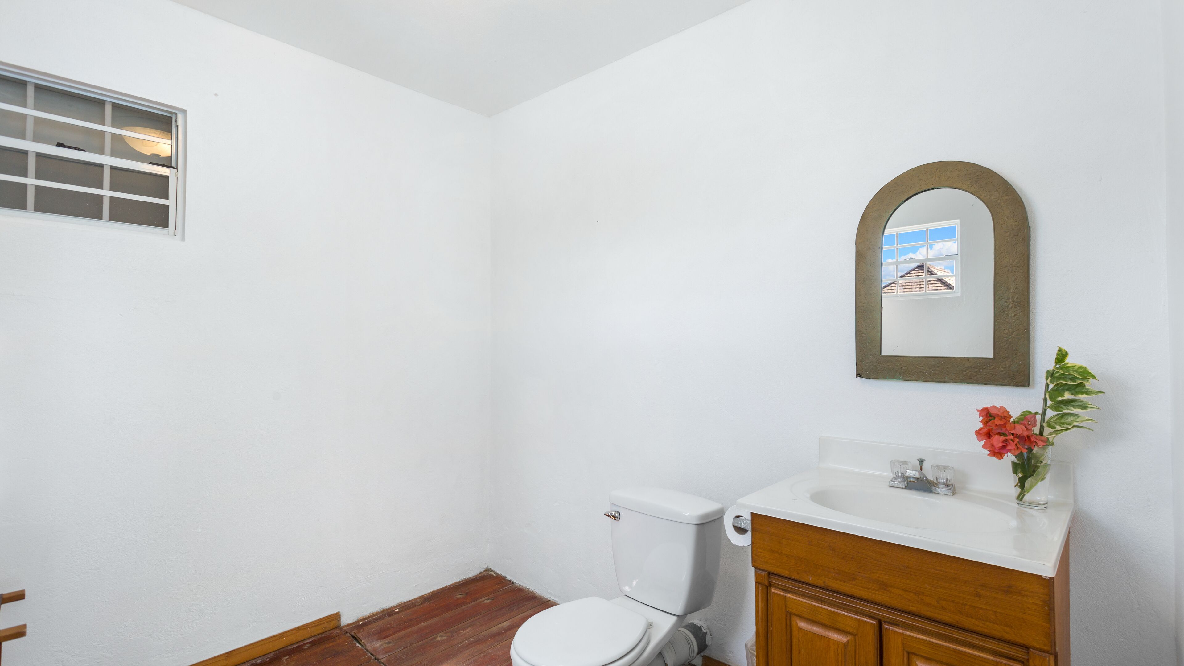Une petite salle de bain blanche, équipée de toilettes, d’un lavabo et d’un miroir.