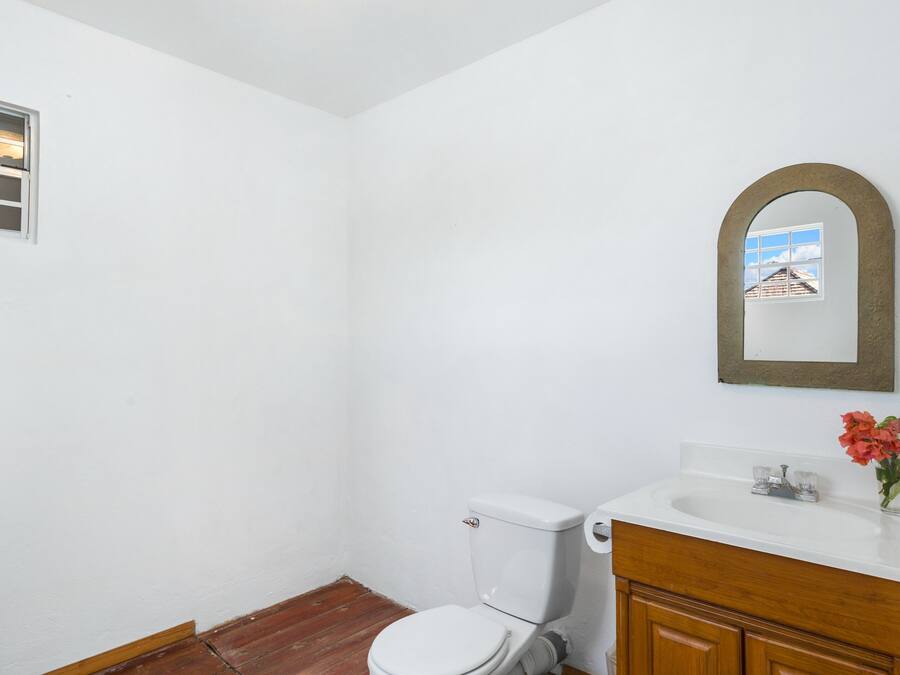 Une petite salle de bain blanche, équipée de toilettes, d’un lavabo et d’un miroir.