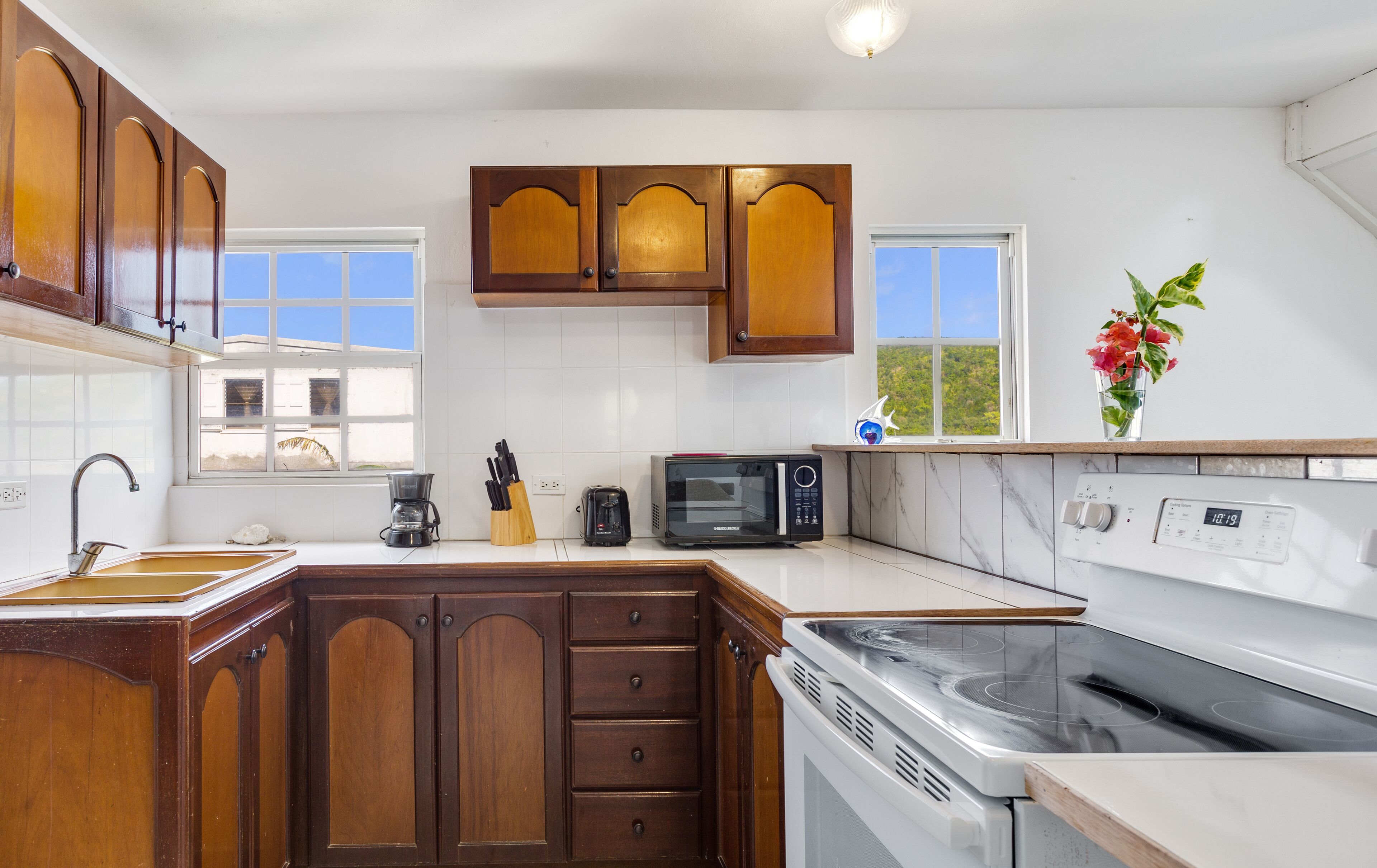 A kitchen with wooden cabinets, a microwave, a stove, and a coffee maker.