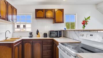 Una cocina con armarios de madera, microondas, estufa y cafetera.