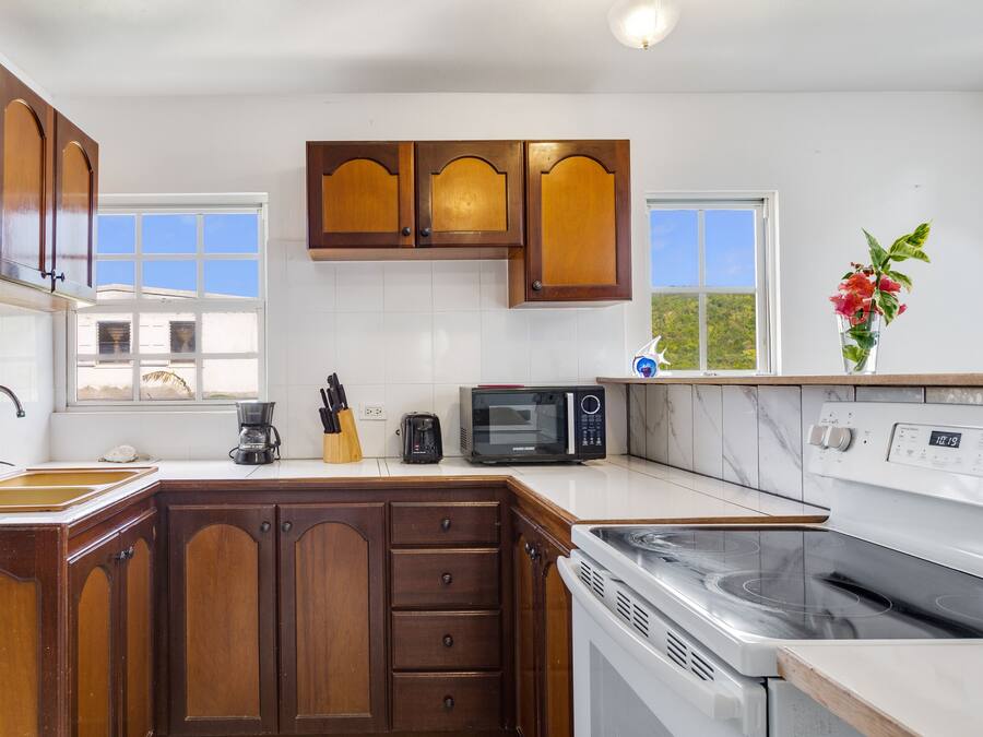Una cocina con armarios de madera, microondas, estufa y cafetera.