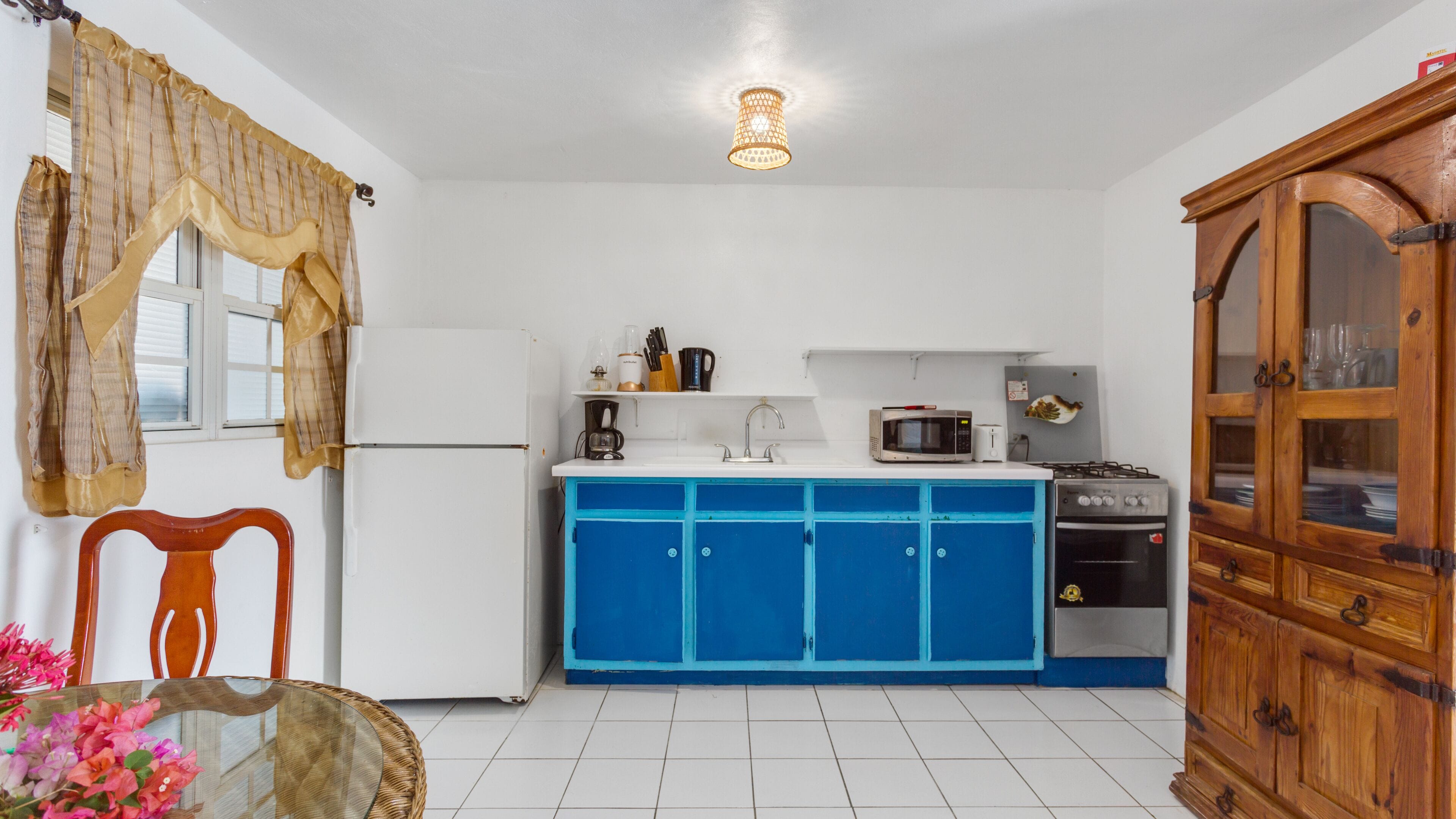 A kitchen with a white refrigerator, blue cabinets, a microwave, and a stove.