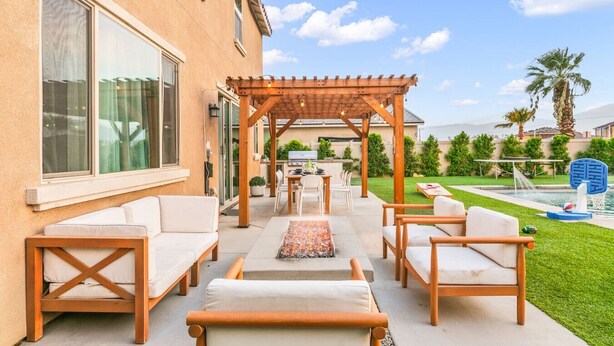 An outdoor patio with a pergola, seating area, and a pool. - NEW 9 bd home w/Pergola|Large Gameroom|Huge Pool (Coachella)