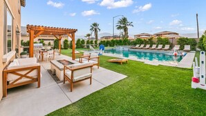 A backyard with a swimming pool, outdoor seating, and a pergola. - NEW 9 bd home w/Pergola|Large Gameroom|Huge Pool (Coachella)