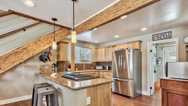 A kitchen with wooden cabinets, a stainless steel refrigerator, and a granite countertop island. - Dancing Bear Cabin Pet Friendly, Sleeps 4, Totally Cute! (South Lake Tahoe)