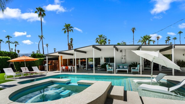 A modern pool area with lounge chairs, a hot tub, and a covered seating area with umbrellas. - Mid-Century Alexander Pool Home Featured in Modernism Week (Palm Springs)