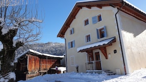 Ein zweistöckiges Gebäude mit verschneitem Dach und Holzfassade.