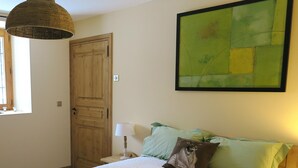 Ein Schlafzimmer mit Bett, Kissen, Lampe, einer Tür und einem Fenster.