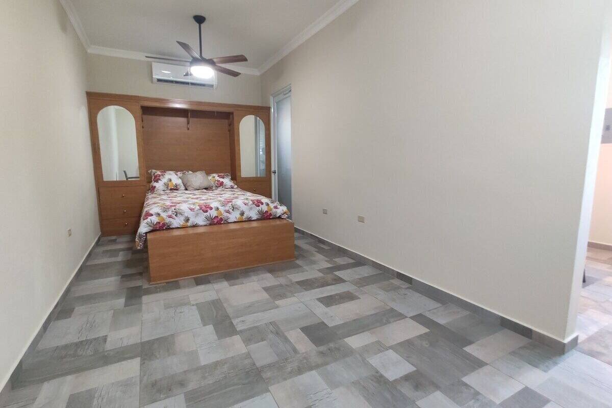 A bedroom with a wooden bed, a ceiling fan, and a tiled floor.