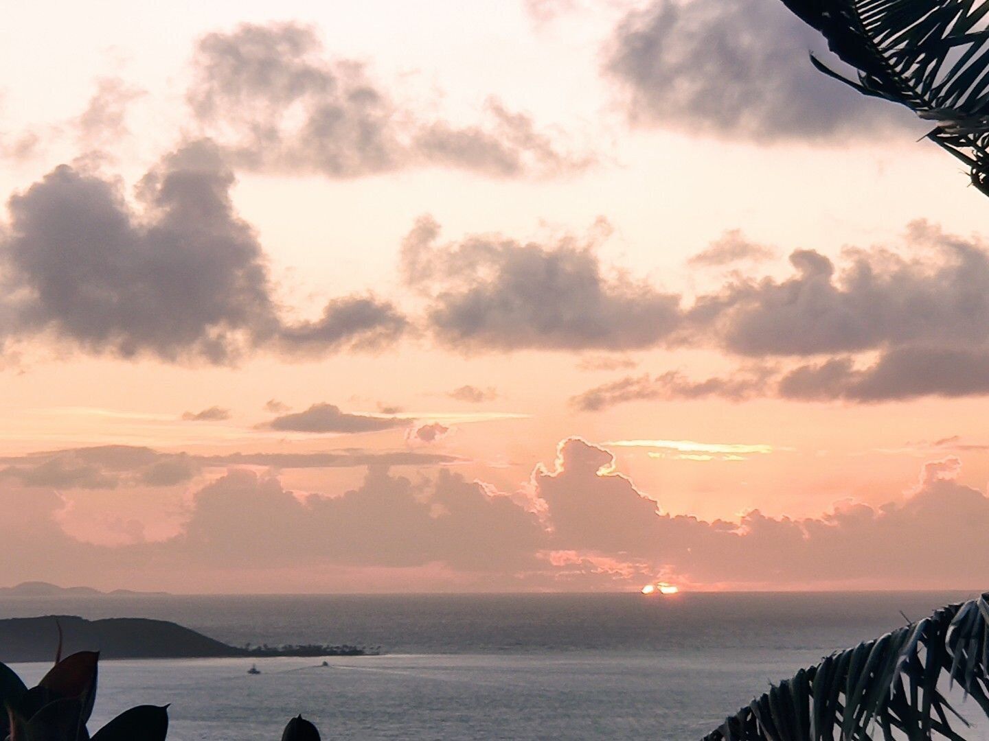 A sunset over the ocean with a clear sky and distant land.