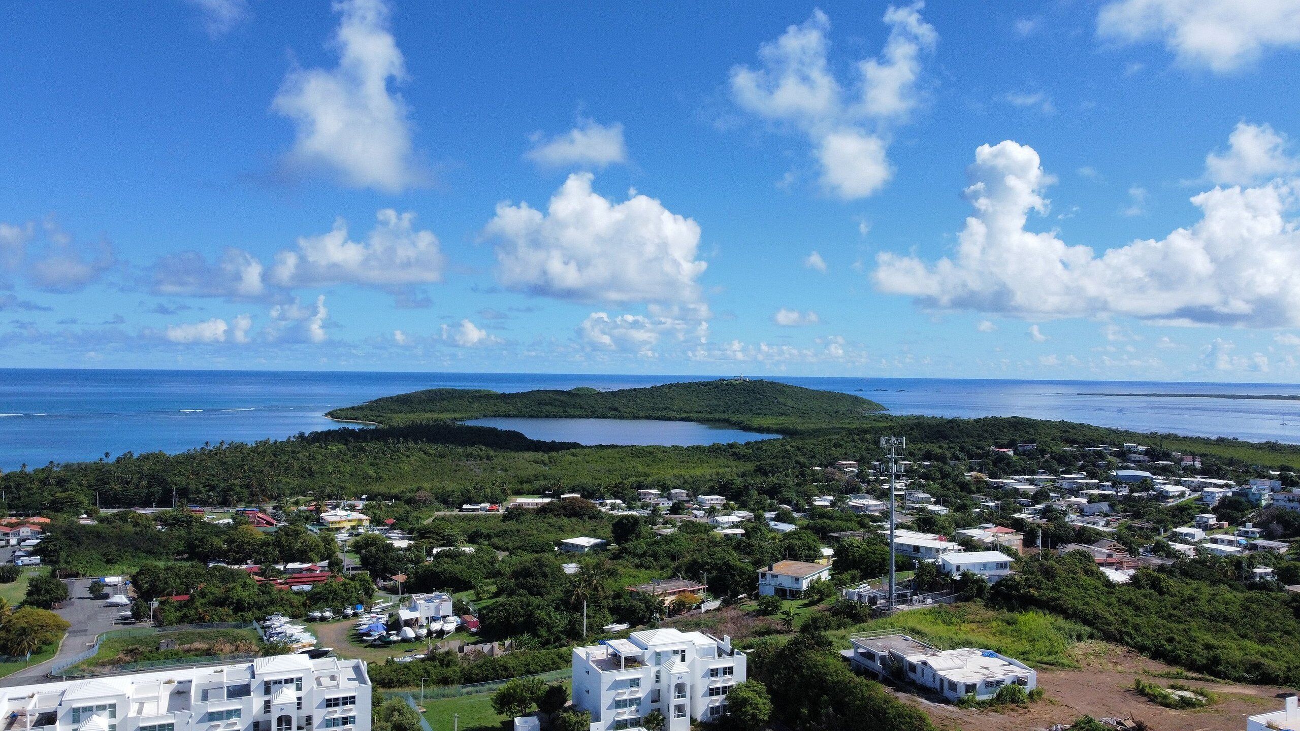 A coastal town with a central island, surrounded by residential buildings and a clear sky.