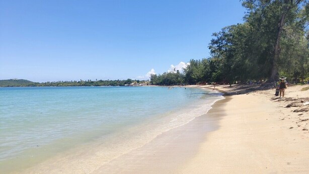 A beach with clear water, a sandy shore, and a few people walking. - Beachfront Studios (Fajardo)