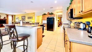 Een moderne keuken met een centraal eiland, houten kastjes en een eethoek met barstoelen.