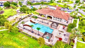 Luchtbeeld van een resort met een zwembad, loungegedeeltes en een groot gebouw met een betegeld dak.