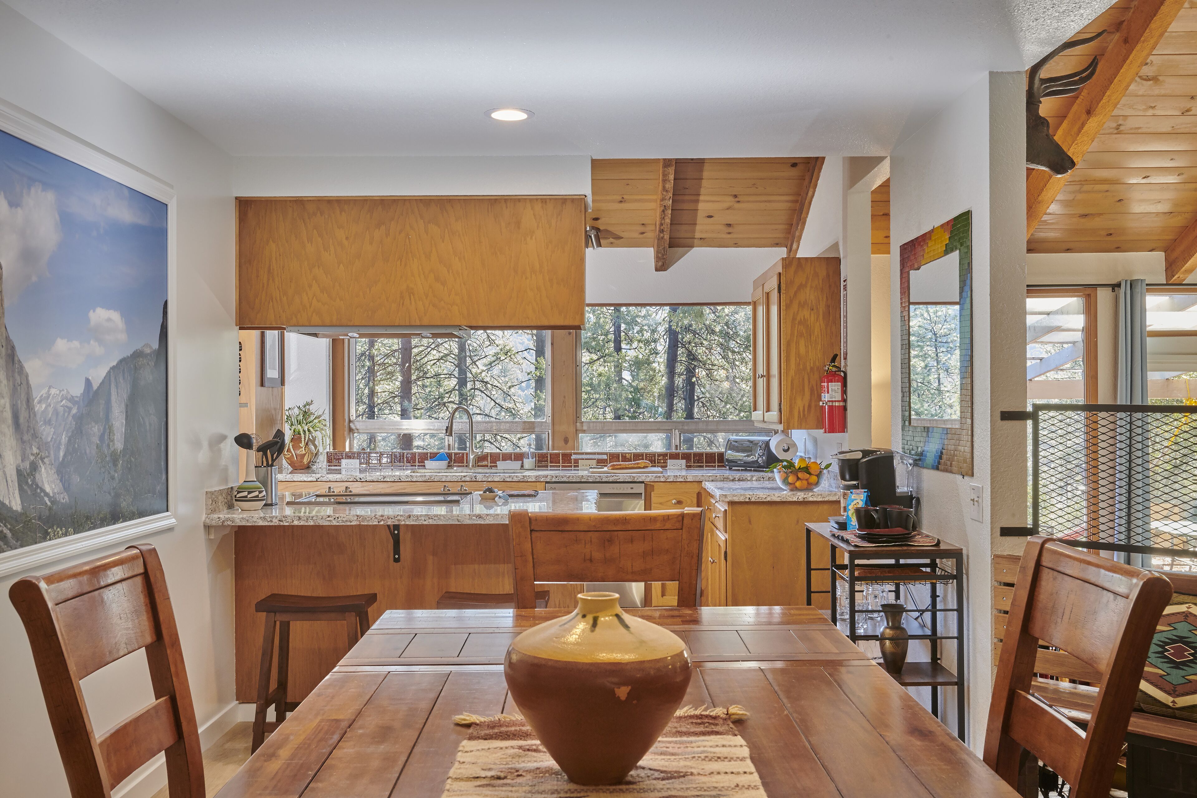 Una cocina moderna con armarios de madera, una isla grande y un comedor con mesa y sillas de madera.