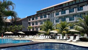 Un hotel con piscina, sillones de descanso y palmeras.