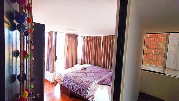 A bedroom with a bed, curtains, and a wall with a brick pattern.