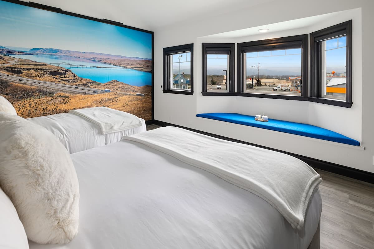 A bedroom with a large bed, a view of a bridge, and a window seat.
