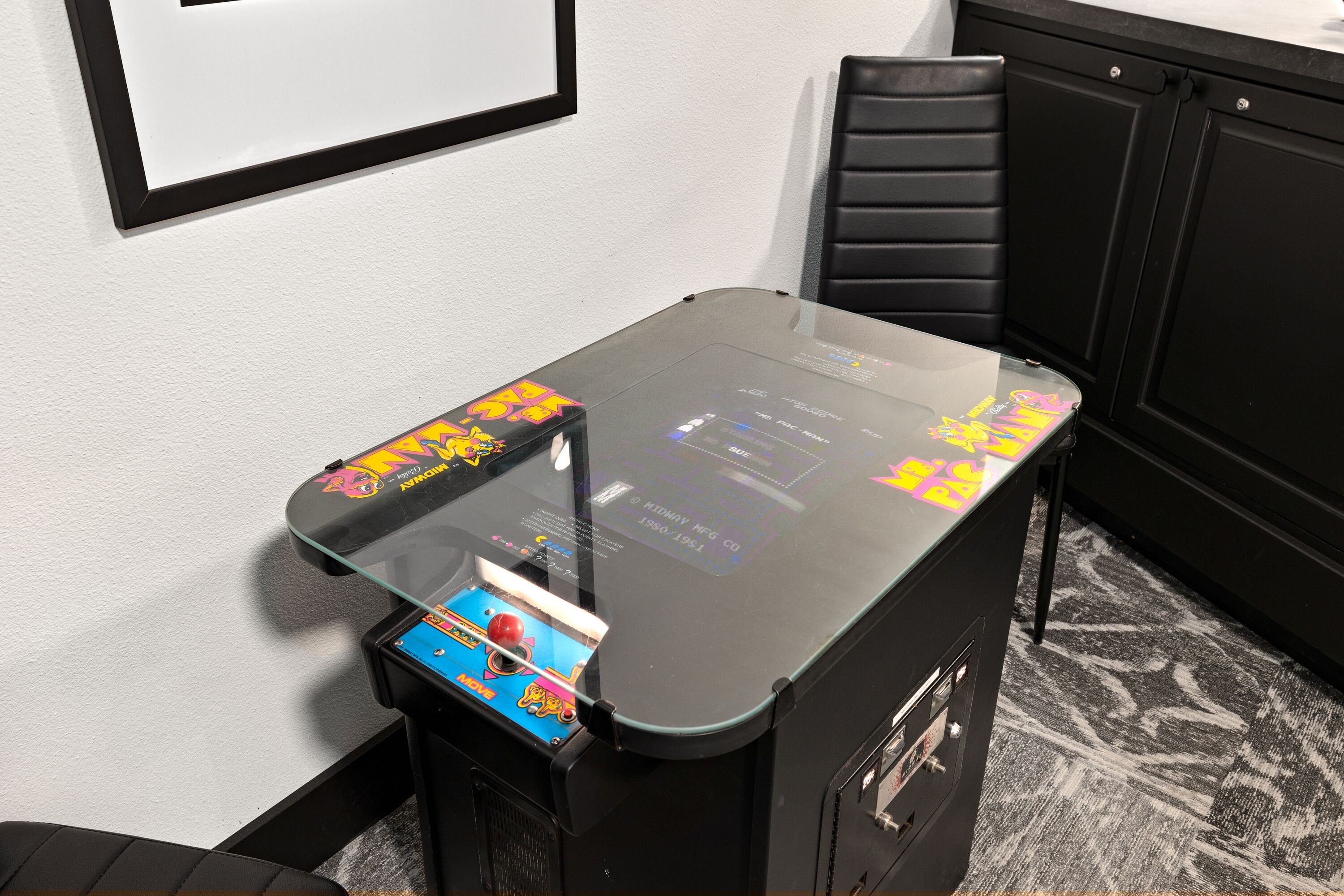 A small room with a glass-top table, a black chair, and a black cabinet.