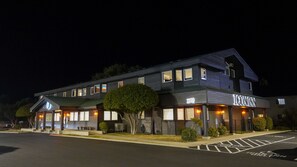 A two-story hotel with a dark facade, illuminated windows, and a sign reading "ICONINN".