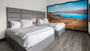A modern bedroom with a large bed, two bedside tables, and a large window with a scenic view. - Icon Inn (Ellensburg)