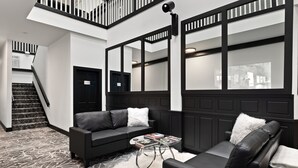 A modern interior with a black leather sofa, a white fluffy rug, and a staircase leading to an upper level. - Icon Inn (Ellensburg)