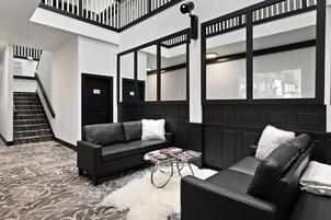 A modern interior with a black leather sofa, a white fluffy rug, and a staircase leading to an upper level.