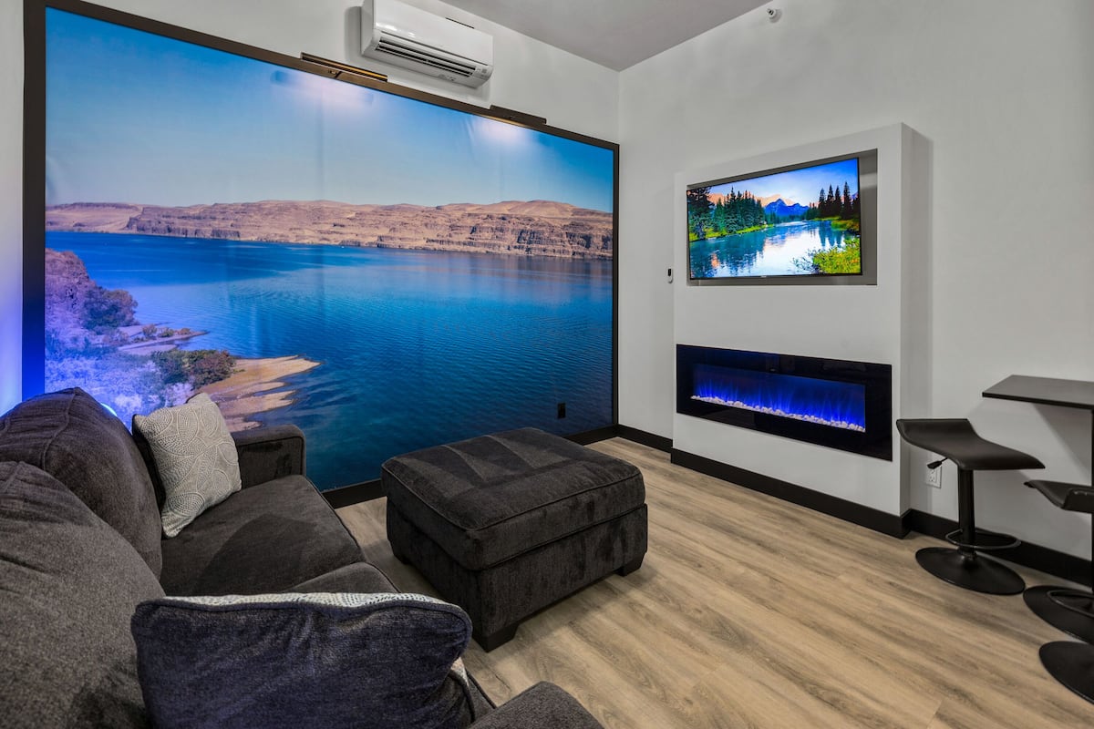 A modern living room with a large wall-mounted TV, a fireplace, and a comfortable seating area.