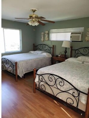 Two single beds with unique headboards, ceiling fan, and air conditioning unit.