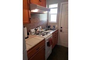Kitchen with gas stove, sink, and oven, adjacent to a door leading to another room.