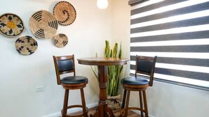 Un comedor con dos sillas de madera, una mesa redonda y adornos tejidos en la pared.