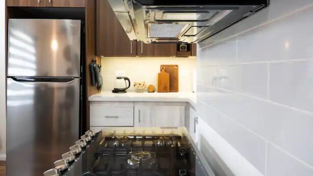Una cocina moderna con electrodomésticos de acero inoxidable, armarios blancos y una estufa a gas.