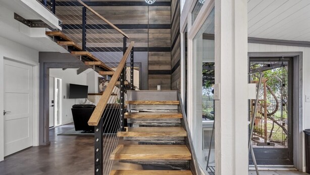Eine moderne Treppe mit Holzstufen und Metallgeländern, die zu einer Glastür führt.