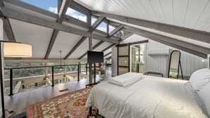 Ein Schlafzimmer mit einem großen Bett, Ausblick ins Freie und einem Oberlicht.