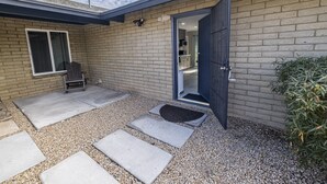 A modern house with a brick exterior, a dark blue door, and a gravel driveway with stepping stones.