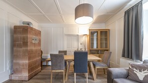 Un coin repas avec une table et des chaises en bois, une cheminée en briques et un grand meuble.