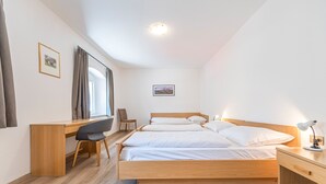 Une chambre à coucher avec un lit en bois, un bureau, une chaise et une table de chevet avec une lampe.