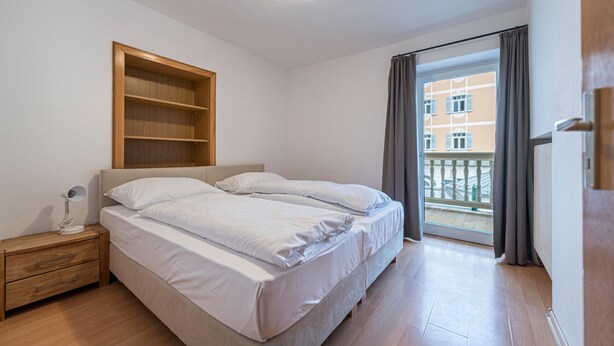 Un dormitorio con cama, mesita de noche y estante empotrado.