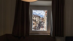 Ein Zimmer mit großem Fenster und Blick auf eine belebte Straße.