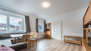 Ett modernt vardagsrum med en soffa, fåtöljer, ett matbord och ett TV-bord.