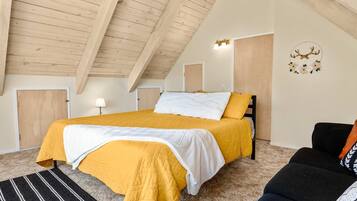 A bedroom with a bed, a sofa, a rug, and a wall decoration.