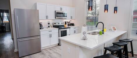 A modern kitchen with white cabinetry, stainless steel appliances, and a central island with bar stools.