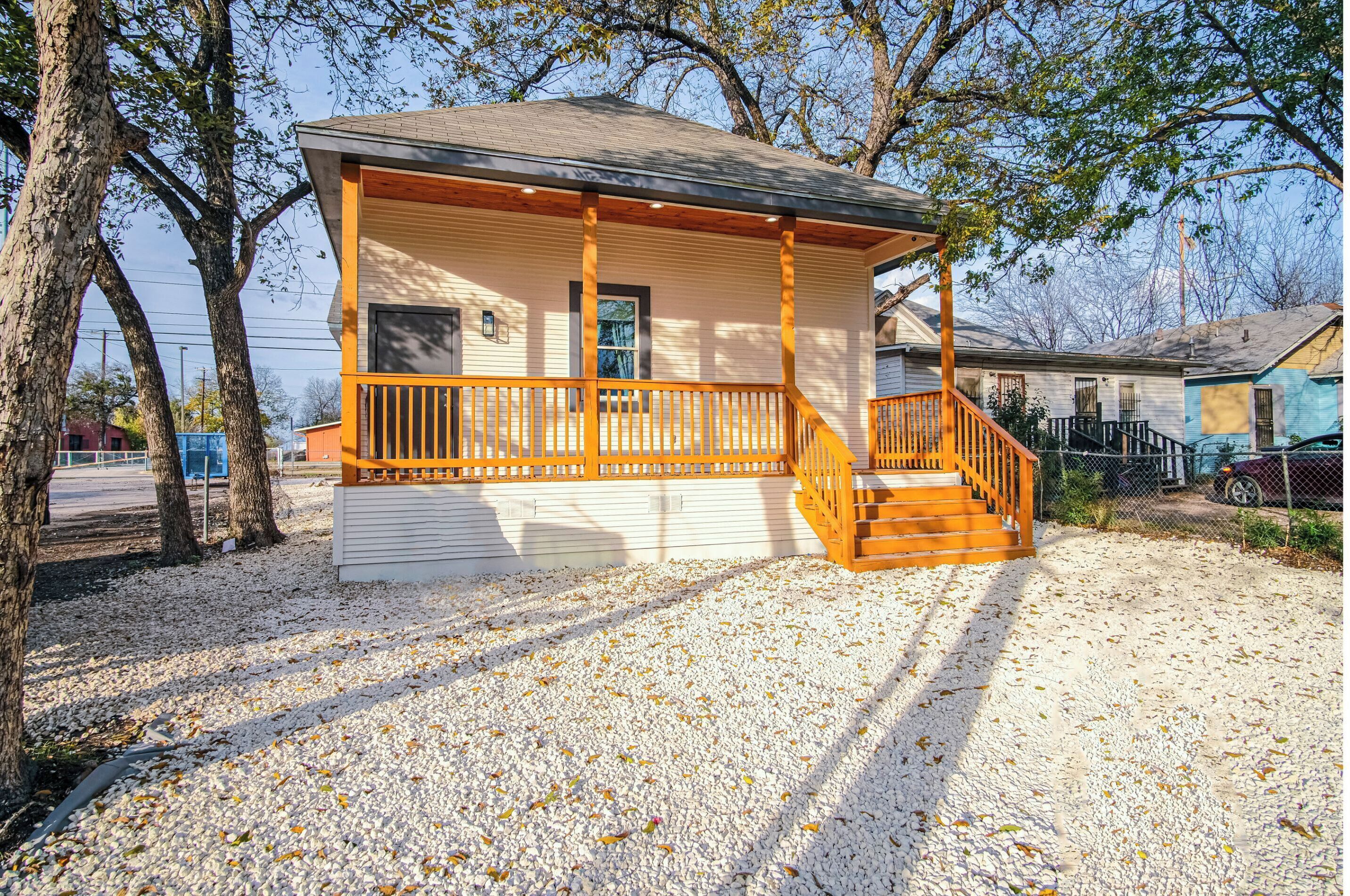 A single-story house with a wooden porch and a staircase leading to the entrance.