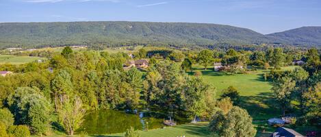 A rural landscape with a pond, houses, and a barn.