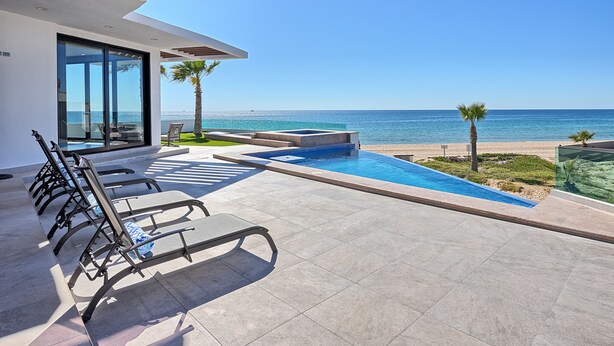 A modern outdoor pool area with lounge chairs, a clear view of the ocean, and a well-maintained patio. - Luxury Oceanfront Home with Pool & Hot Tub - located on Sandy Beach (Puerto Peñasco)