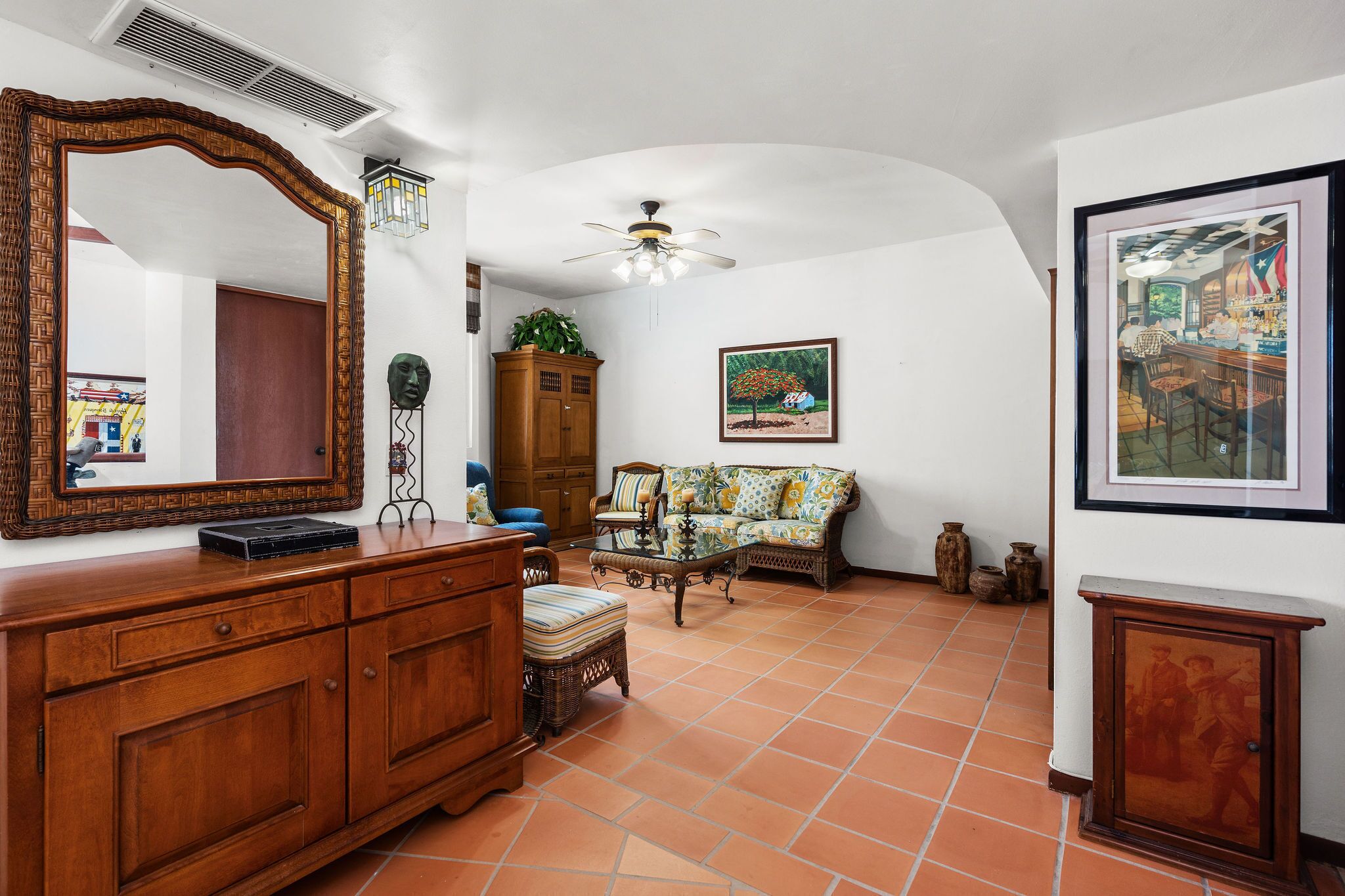 A spacious room with a large wooden cabinet, a sofa, a dining table, and a ceiling fan.