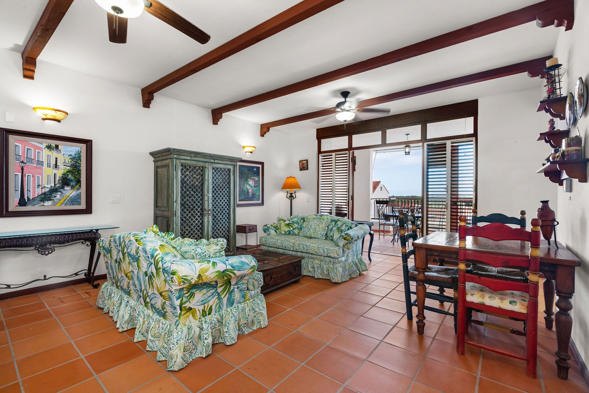 A spacious living room with a sofa, a dining table, and a ceiling fan.