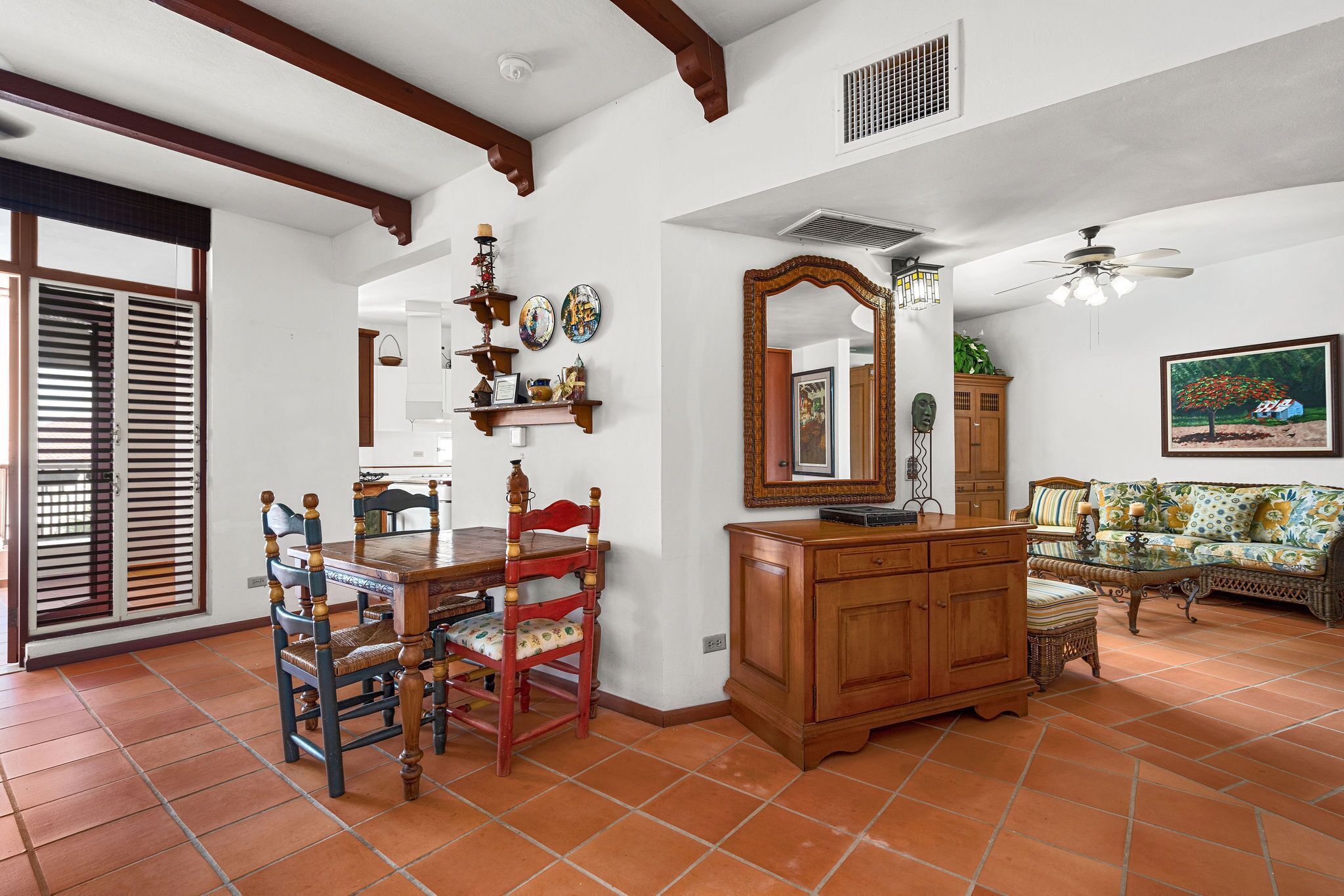 A dining area with a wooden table and chairs, a sofa, and a ceiling fan.