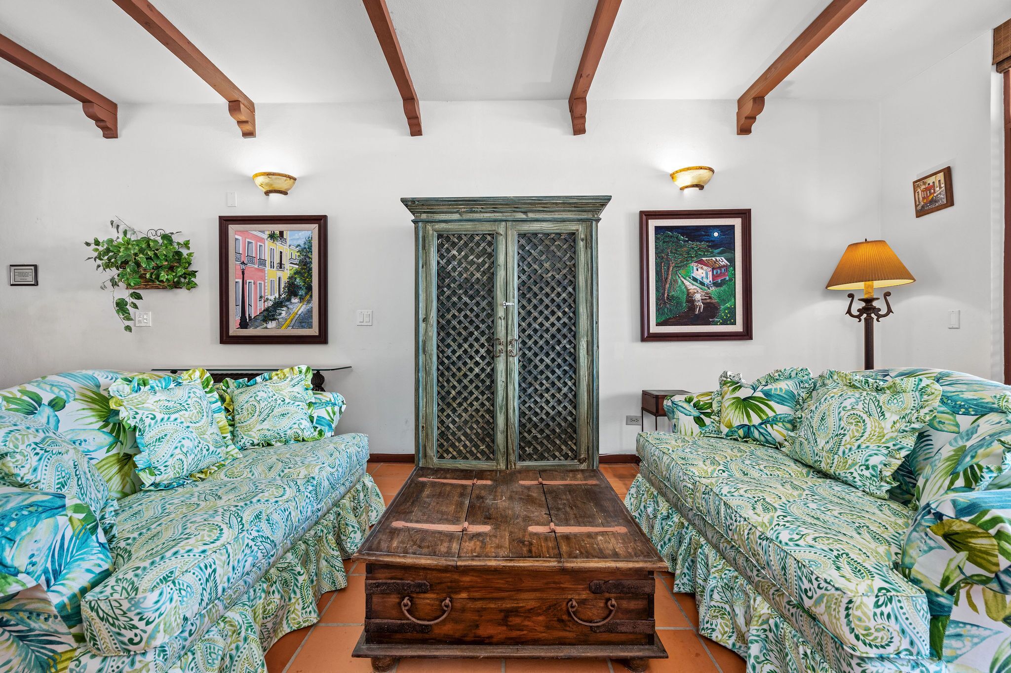 Ein Zimmer mit zwei gestreiften Sofas, einer Holzkiste und einem grünen Schrank mit Rautenmuster.