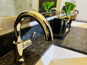 A modern kitchen with a stainless steel faucet, granite countertops, and a black sink.